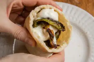 Assembling tamales de rajas con queso with masa, roasted rajas, and cheese on corn husk