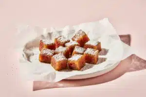 Fried watermelon pieces draining and sprinkled with powdered sugar