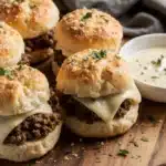 Garlic parmesan cheeseburger bombs fresh from the oven on wooden platter with garlic aioli