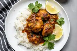 Plated moes adobo chicken​ with rice and garnishes