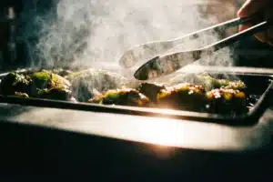 Roasting poblano peppers over flame for tamales de rajas con queso filling