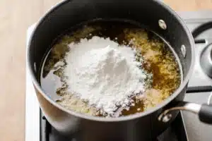 How to Make the Perfect Asiago Cream Sauce (Best Recipe + Tips) 5 All-purpose flour being stirred into butter to make roux for Asiago cream sauce