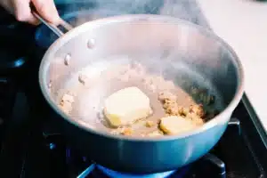 How to Make the Perfect Asiago Cream Sauce (Best Recipe + Tips) 4 Butter melting with minced garlic sautéing in a saucepan for Asiago cream sauce