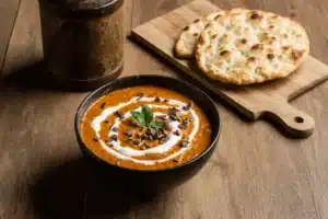 Authentic Makhani Sauce Recipe | Easy Butter Chicken Sauce 9 Serving bowl and storage container of makhani sauce with naan bread